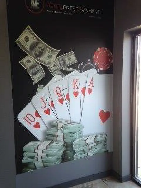 Ace Entertainment interior wall mural — bold black backdrop with oversized printed playing cards, poker chips, and cascading currency.
