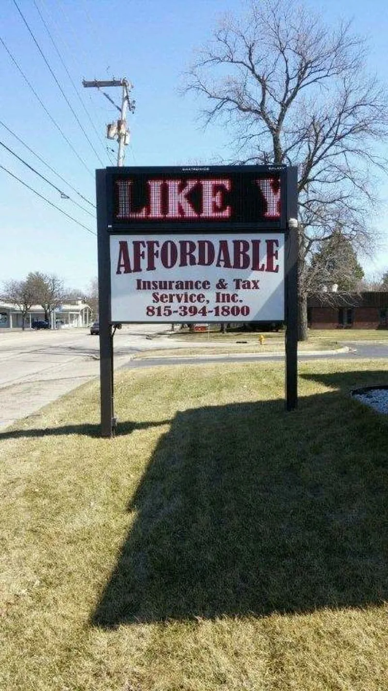 Affordable Insurance & Tax Service free-standing post-and-panel monument — two-post mount with white tenant panel below and a red-LED message screen across the top, on a roadside lawn.