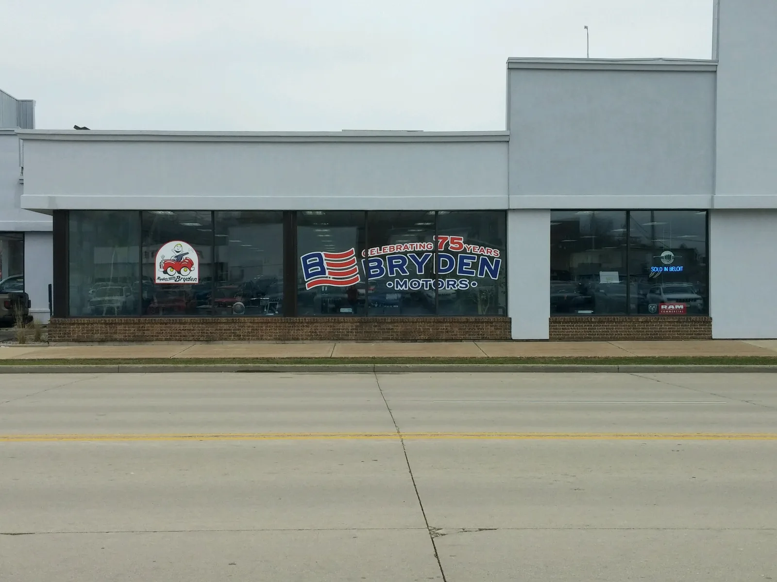 Bryden Motors dealership storefront — printed window graphics celebrating 75 years with American flag emblem applied to glass.