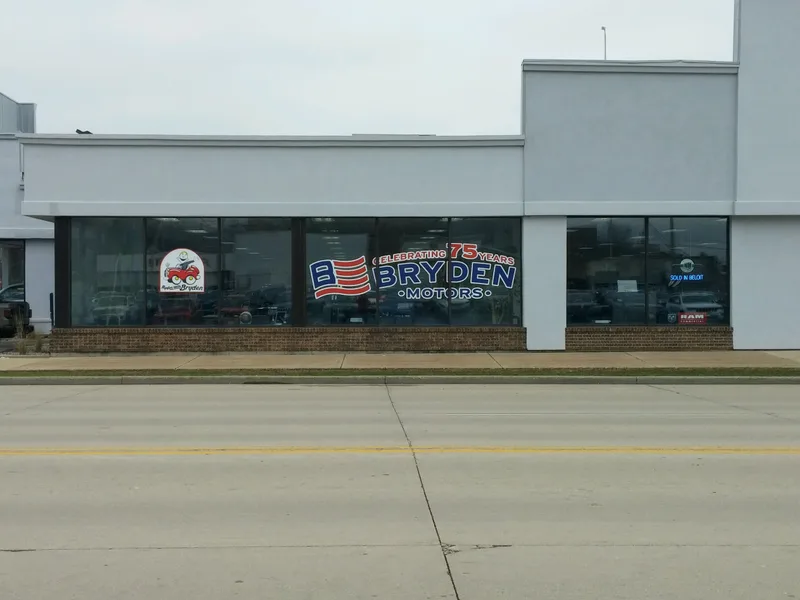 Bryden Motors dealership storefront — printed window graphics celebrating 75 years with American flag emblem applied to glass.