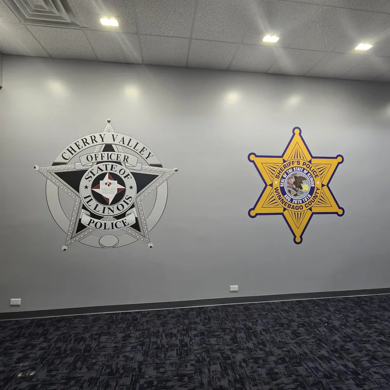 Cherry Valley Police and Winnebago County Sheriff badge wall graphics side by side on a gray accent wall inside the PSR Center.