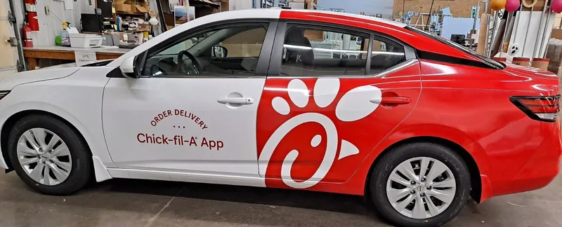 Chick-fil-A delivery sedan — half wrap in signature red with the white cow-spot "C" logo and "Order Delivery — Chick-fil-A App" on the front door.