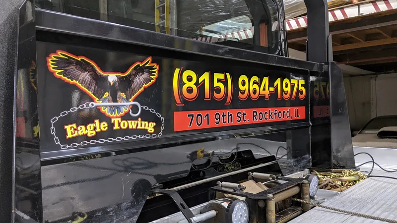 Eagle Towing tow-truck headboard graphics — airbrush-style eagle-and-chain logo with "(815) 964-1975" and "701 9th St. Rockford IL" in bold orange and red.