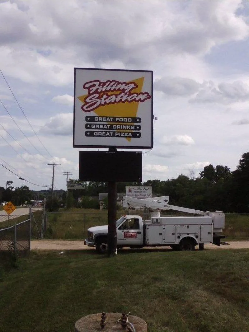 Filling Station pylon sign mid-install — CorPro bucket truck parked at the base of a freshly mounted pole sign with LED message panel.