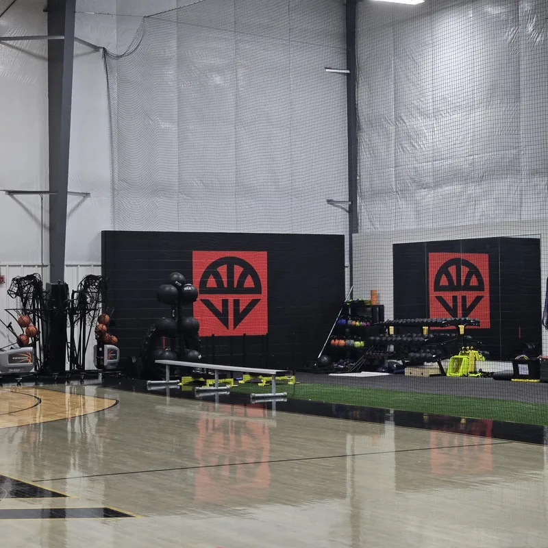 Foundation Sports Gym training area — matching red-and-black square logo graphics painted on two black block walls behind the turf and court.