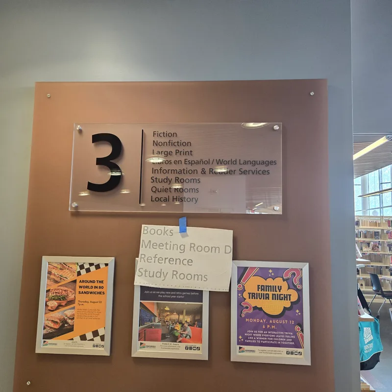 Fountaindale Public Library (Bolingbrook) interior wayfinding — acrylic stand-off panel showing floor '3' with collection categories (Fiction, Nonfiction, Large Print, Libros en Español / World Languages, Information & Reader Services, Study Rooms, Quiet Rooms, Local History) on a peach-colored backer wall.