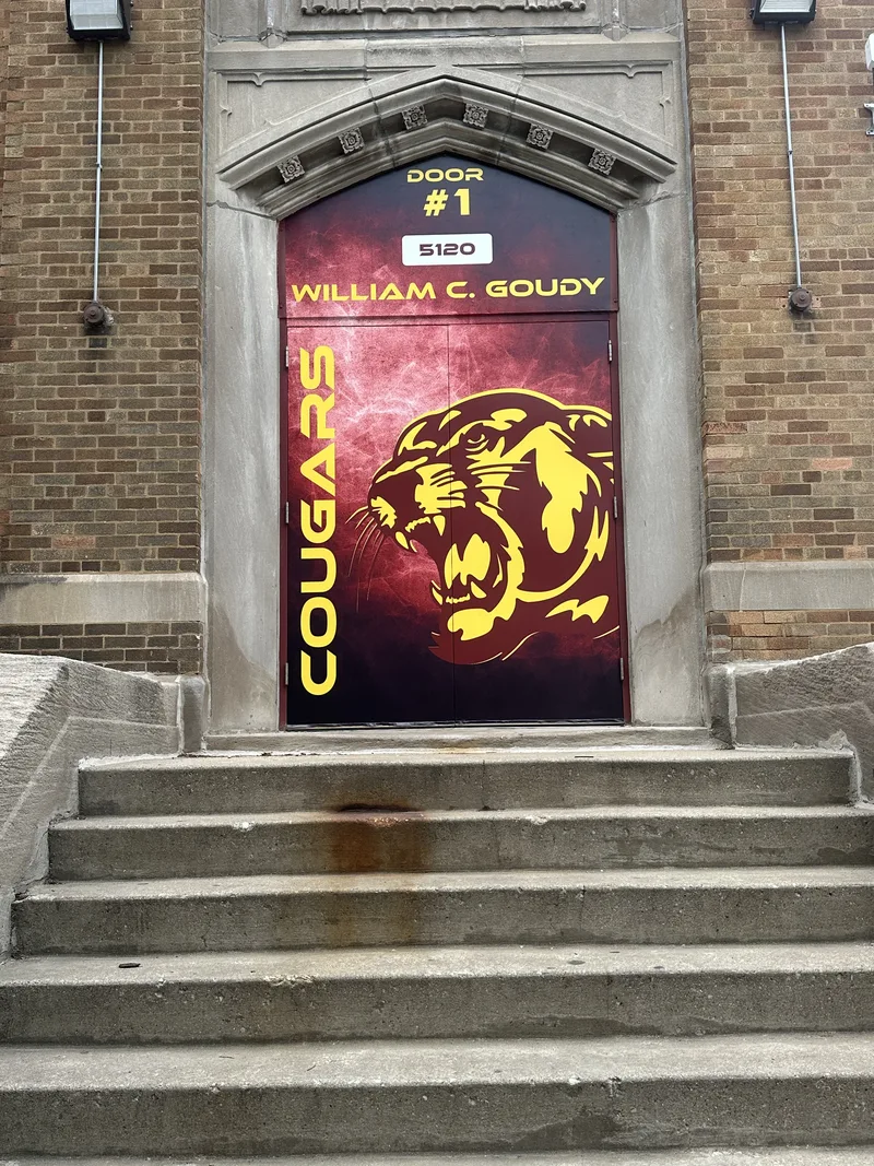 William C. Goudy School entry — full-door "COUGARS" mascot wrap with door number and school name, set into a historic carved-stone doorway.