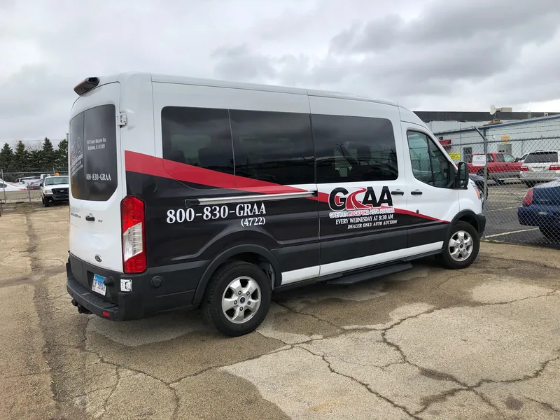 Greater Rockford Auto Auction (GRAA) passenger van — white Ford Transit with a black-and-red swoosh wrap, GRAA logo and "800-830-GRAA" on the rear quarter.