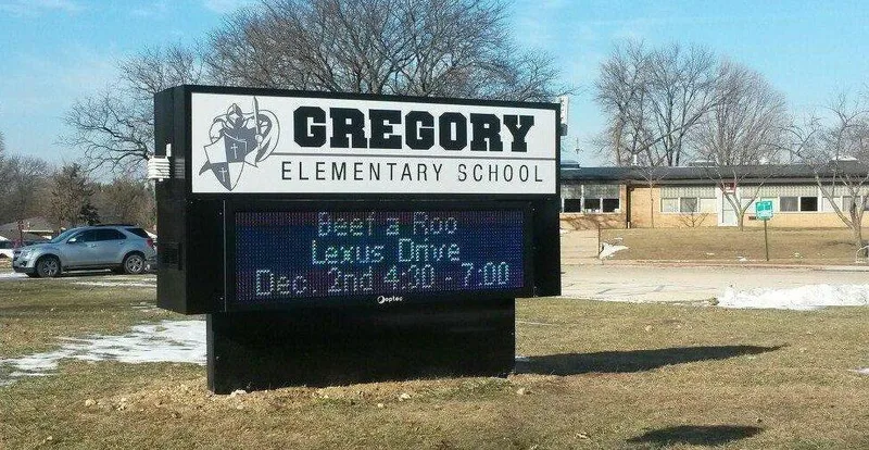 Gregory Elementary School monument — white cabinet with the school mascot and name above a full-color LED message board, on a black base.
