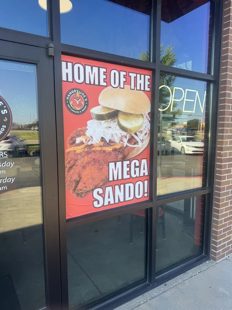 Hangry Joe's storefront window graphic — bright red 'HOME OF THE MEGA SANDO!' full-color printed window vinyl featuring the rooster-logo circle and a photorealistic pickled-slaw chicken sandwich, mounted on the entrance-door glass.