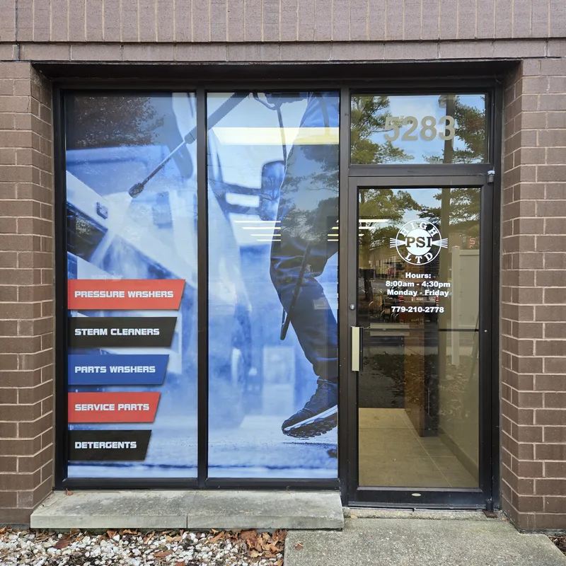 High PSI Ltd. storefront — full-height printed window graphic of a pressure-washer operator with red product-category tabs, plus logo and hours vinyl on the entry door.
