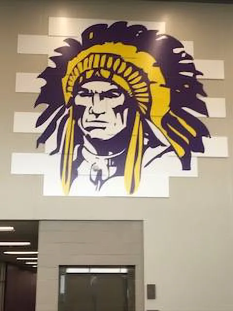 Hononegah High School interior chief mural — purple, yellow, and white painted dimensional wall graphic of the school mascot.