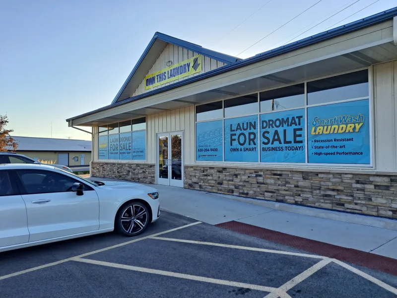 Smart Wash Laundromat storefront — full-coverage printed window graphics in blue and yellow advertising the business across multiple bays.
