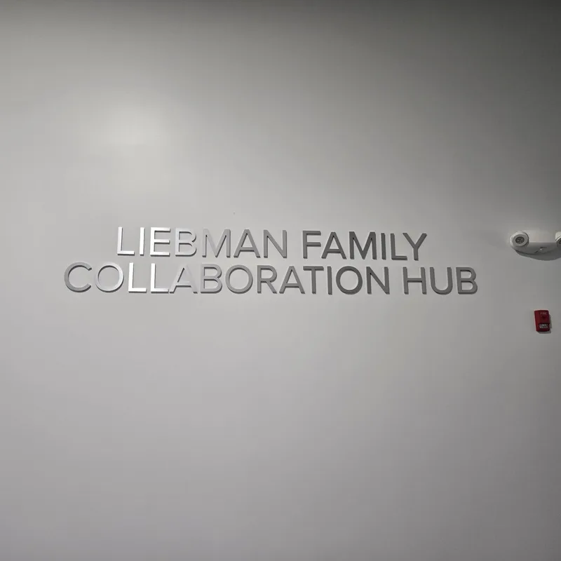 McHenry County College Liebman Family Collaboration Hub — brushed-metal dimensional letters reading 'LIEBMAN FAMILY COLLABORATION HUB' mounted on a clean light-gray interior wall.