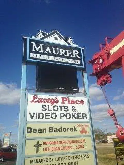 Maurer Real Estate Group multi-tenant pylon sign topped with a Victorian-styled cabinet and LED message screen, with installation crane in frame.