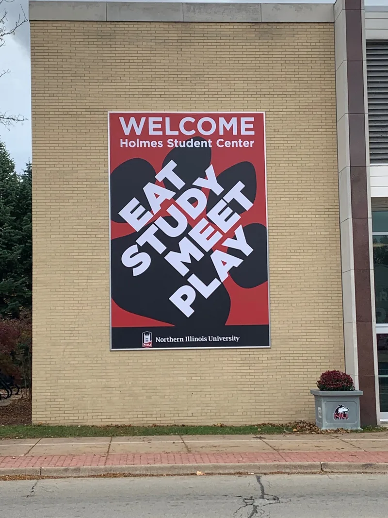 Vertical NIU Holmes Student Center wall banner — red paw print with "EAT STUDY MEET PLAY" overlay.