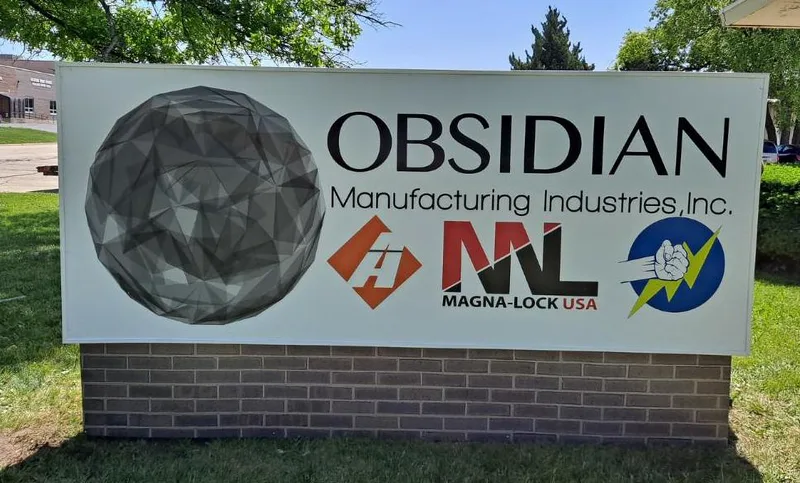 Obsidian Manufacturing Industries corporate monument sign — brick-based panel monument featuring the 'OBSIDIAN Manufacturing Industries, Inc.' wordmark with a geometric obsidian-sphere graphic on the left, plus sub-brand logos for A/H, Magna-Lock USA, and TeamBest Global.