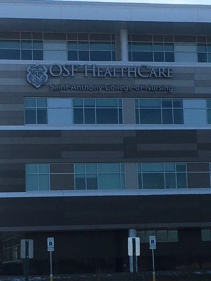 OSF HealthCare Saint Anthony College of Nursing — brushed-metal dimensional letters and crest mounted on the multi-story panel facade.