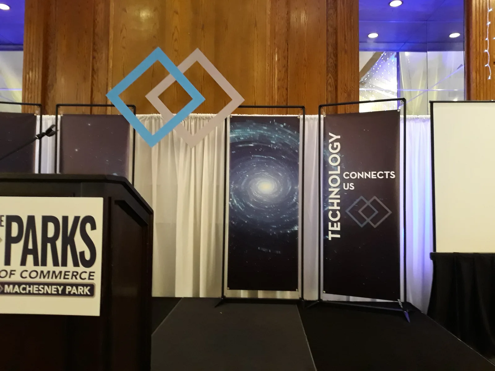 Machesney Park Chamber of Commerce branded event — printed banner stands with a "Technology Connects Us" backdrop and matching podium graphic.