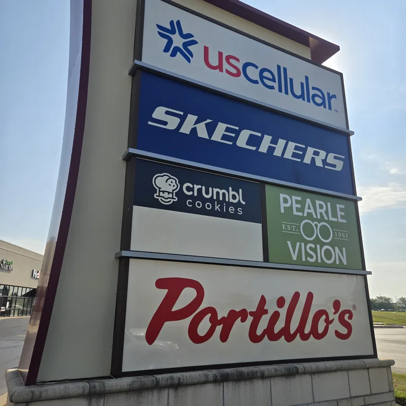 Multi-tenant shopping-center pylon — US Cellular, Skechers, Crumbl Cookies, Pearle Vision and Portillo's tenant panels in a curved architectural frame.