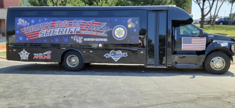 Winnebago County Sheriff transport coach with a full-length custom vehicle wrap featuring a patriotic 4th of July design.