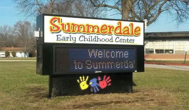 Summerdale Early Childhood Center sign — colorful lit cabinet over a full-color LED board reading "Welcome to Summerdale," with painted handprints on the base.