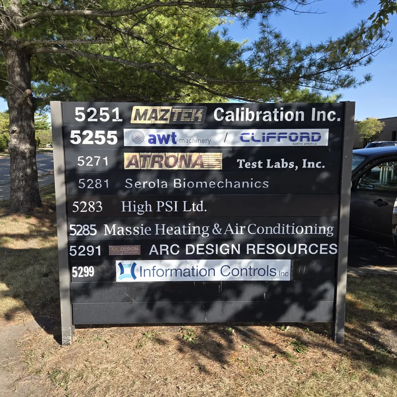 Business-park tenant directory — dark post-and-panel sign with address numbers and replaceable tenant strips (MazTek Calibration, AWT/Clifford, Atrona Test Labs, High PSI, Massie Heating & Air and more).