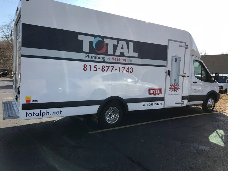 Total Plumbing & Heating box truck — navy stripe with TOTAL logo, phone number, Bryant badge and furnace promo on a white cutaway body.