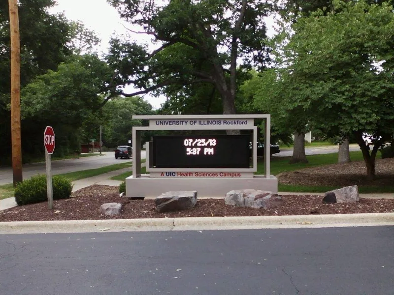 University of Illinois Rockford entrance monument — aluminum frame with an LED time-and-date display above a "UIC Health Sciences Campus" base in a landscaped bed.