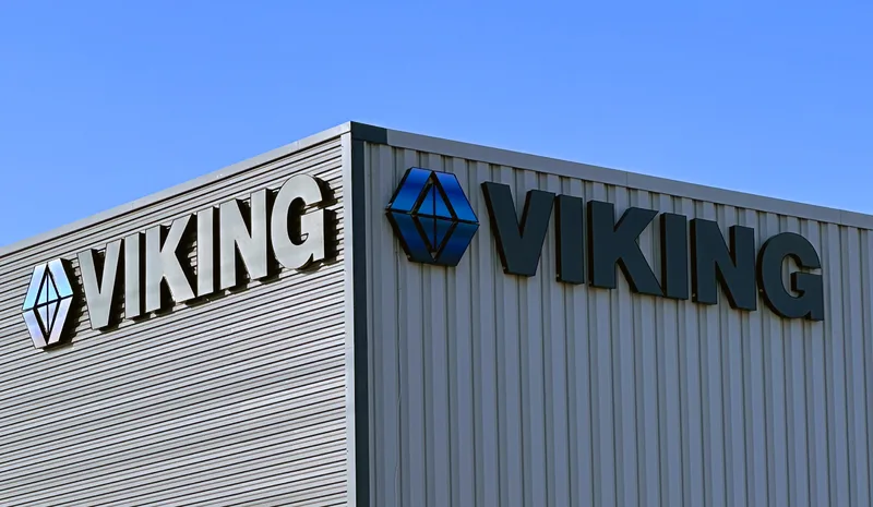 Viking Chemical building corner — brushed-metal and dark dimensional "VIKING" letters with blue diamond logos wrapping both faces of a corrugated-metal facade against a clear blue sky.