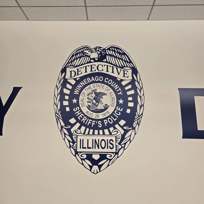 Navy Winnebago County Sheriff's Police Detective badge wall graphic between oversized "WINNEBAGO COUNTY DETECTIVE BUREAU" letters.
