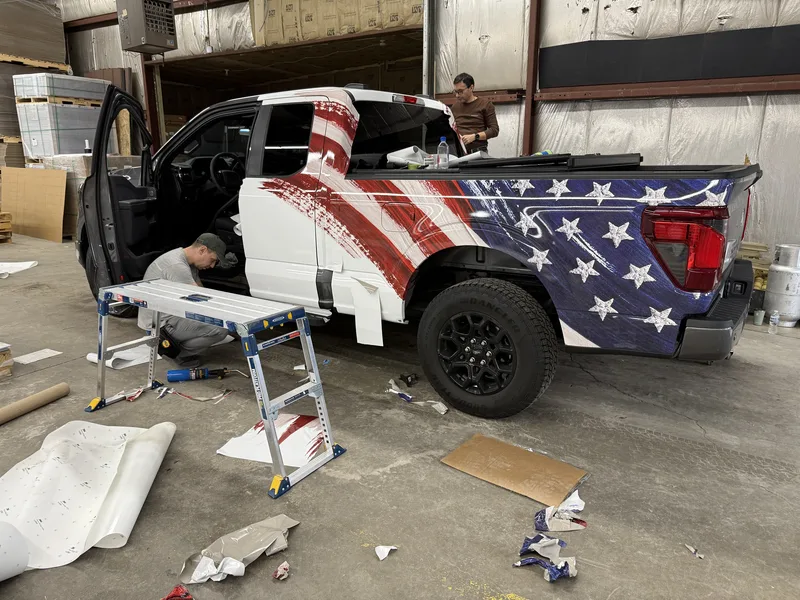 DURING: CorPro installers applying the American-flag wrap panels to the Sheriff's F-150 in the shop.